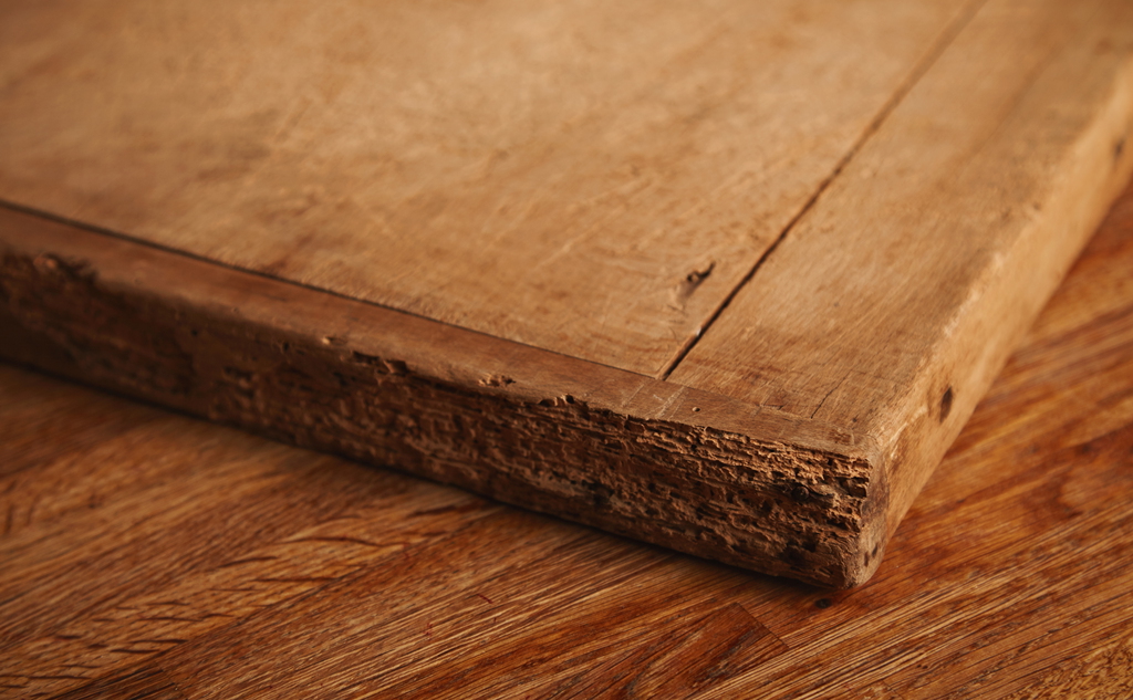 close up shot very old battered chopping board with deep cuts pieces missing lying rustic wooden table